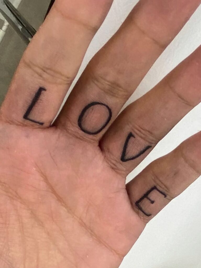 LOVE lettering tattoo across the fingers