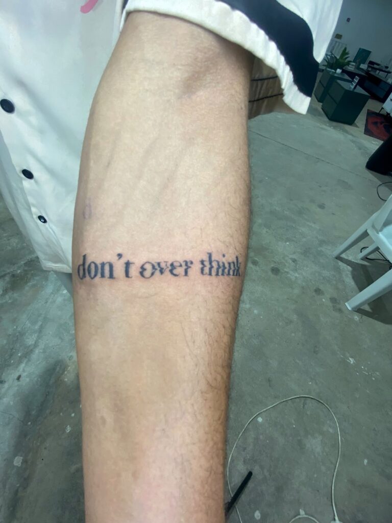 “Don’t overthink” script tattoo on the forearm