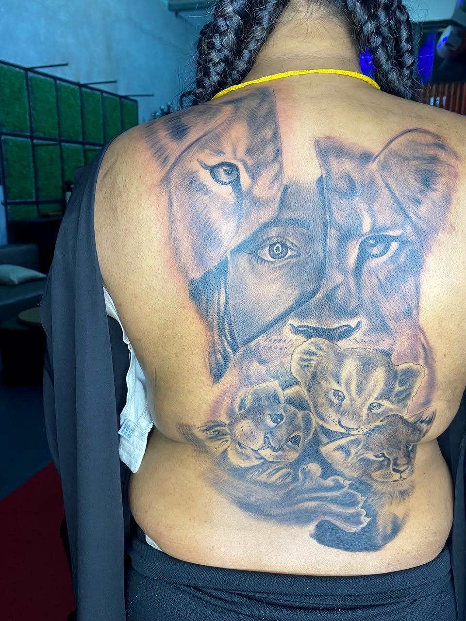 Large black-and-grey lion family back tattoo by Woke Tattoo Studio