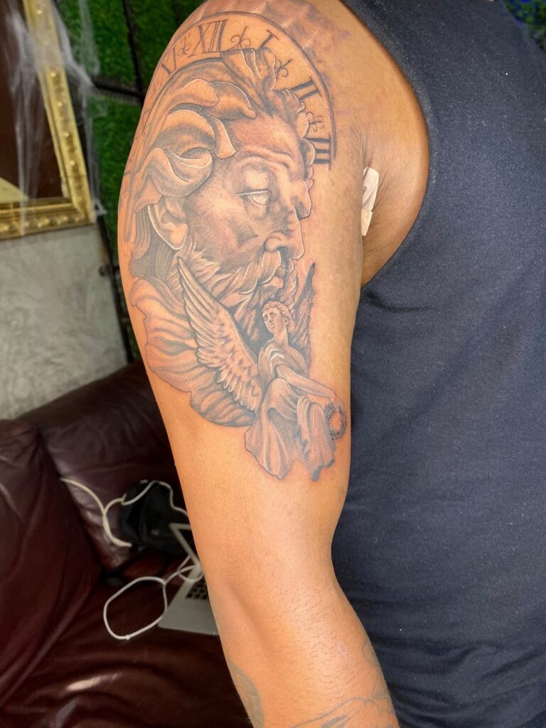 Black and grey portrait tattoo on the upper arm