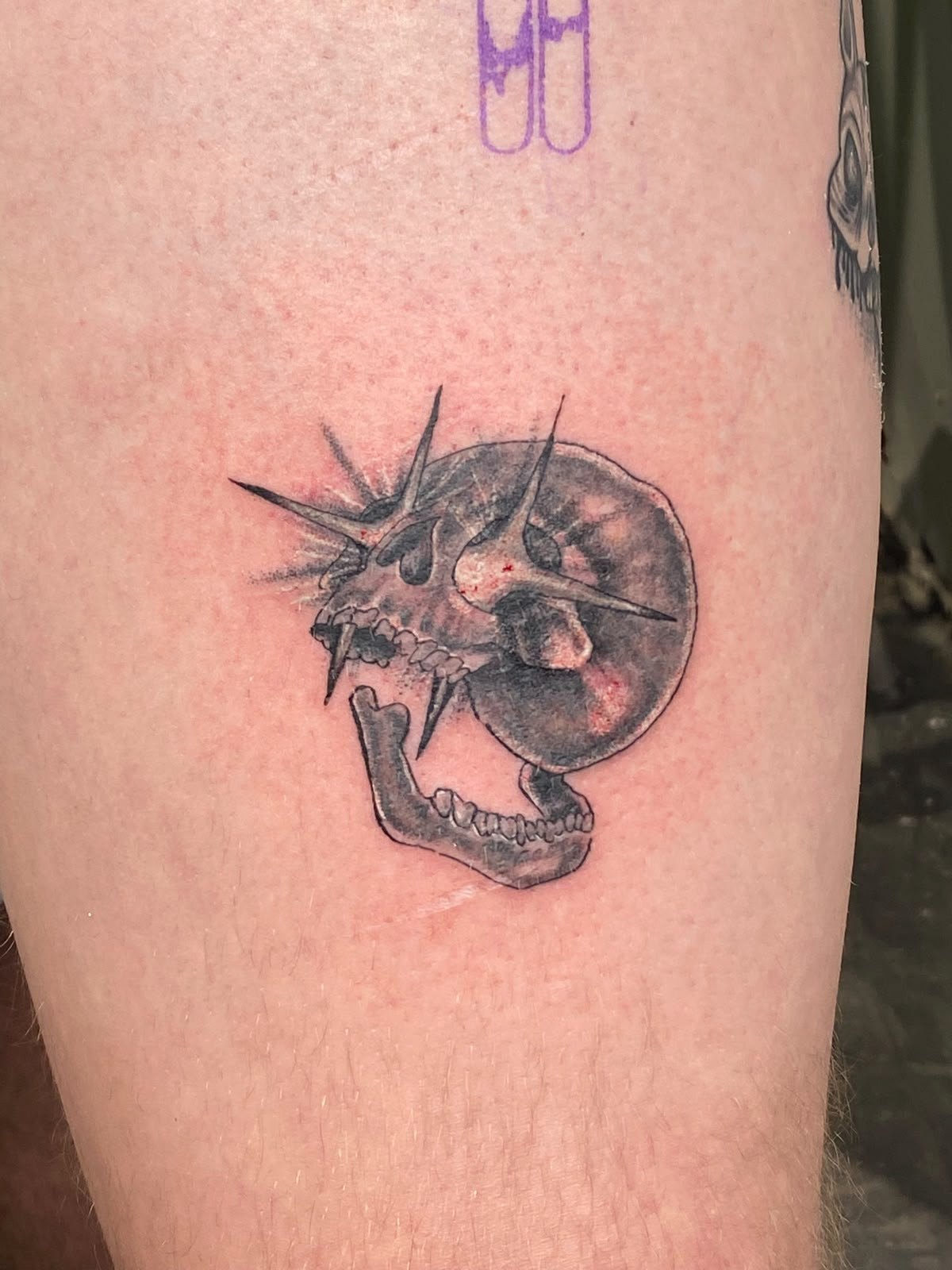 Black-and-grey spiked skull tattoo by Woke Tattoo Studio