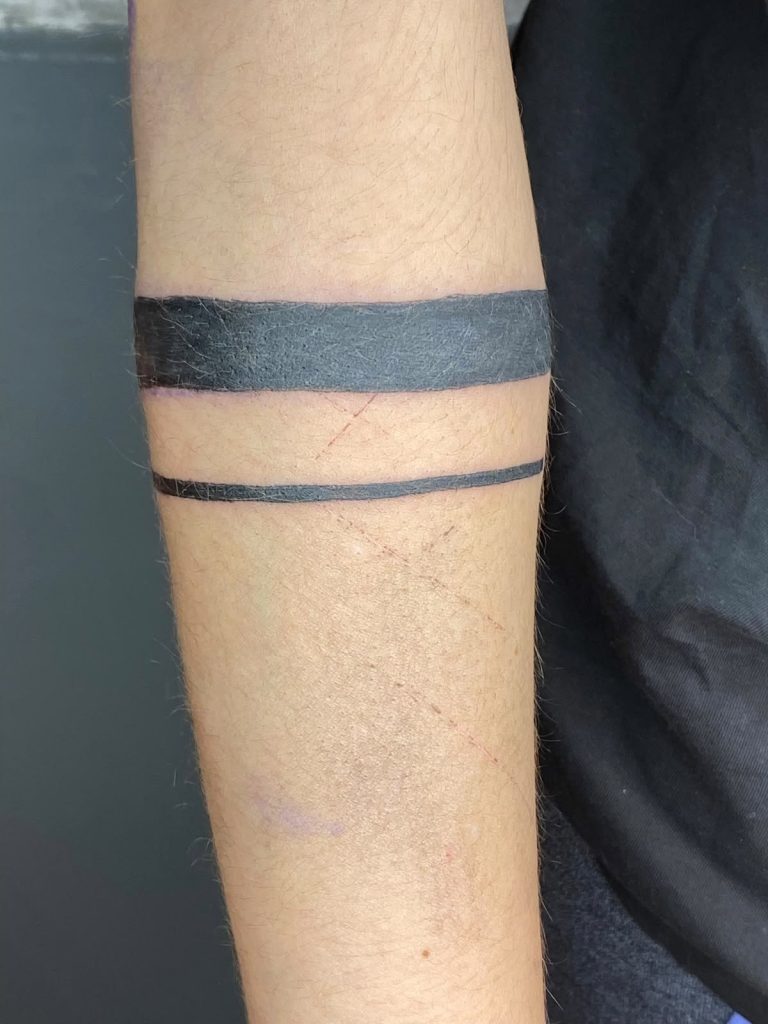 Solid black armband tattoo on the forearm