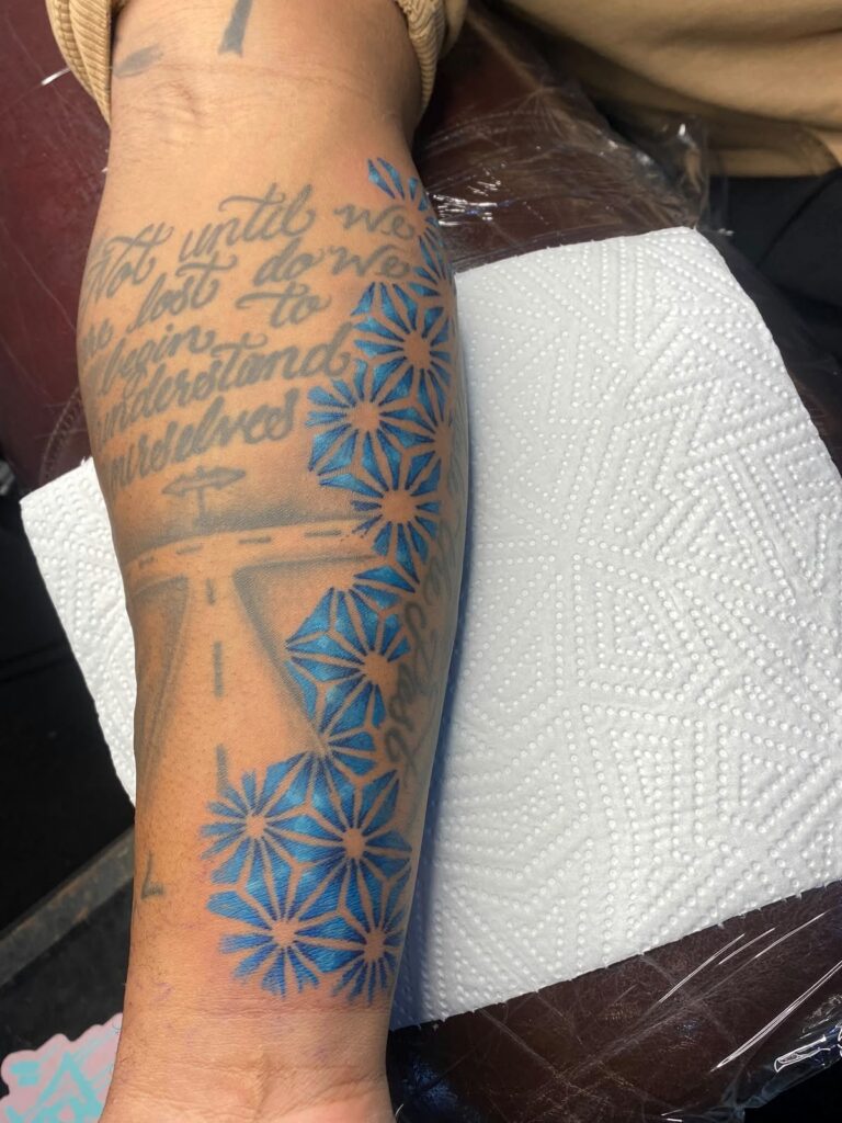 Colour floral and script tattoo on the forearm